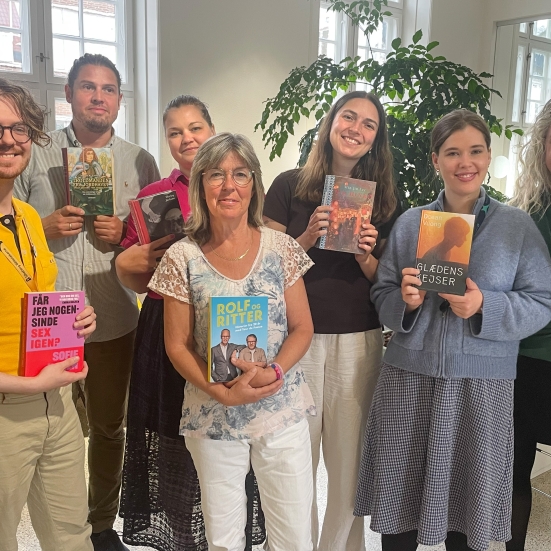 Foto af 7 mennesker med en bog i hånden