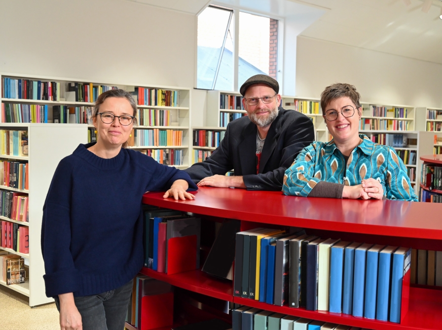 Britt, Frederik og Anne ved rød bogreol